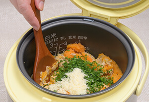 炊き上がったらパセリのみじん切り、粗びき黒こしょう、粉チーズをふりかけ、しゃもじで切るように混ぜ込む。