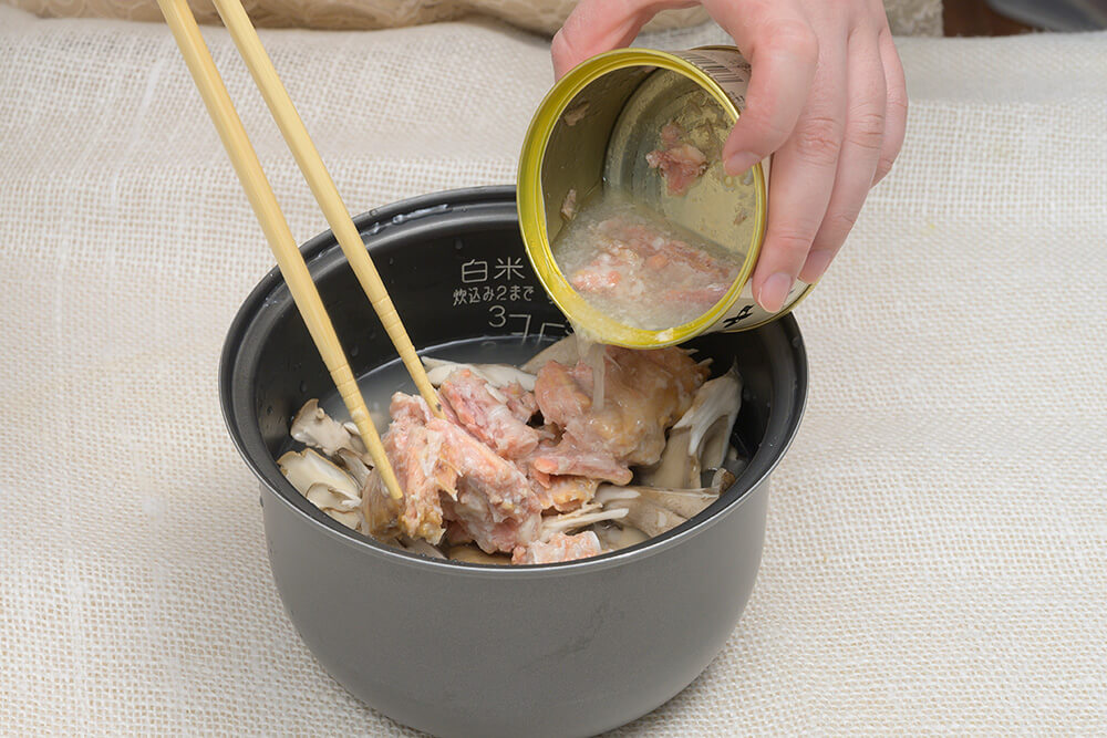 釜に①と水煮の缶汁、塩を入れ、2合まで水をそそぐ。米の上にマイタケと鮭の水煮をのせて炊き上げる。