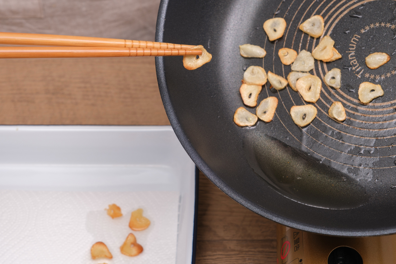 フライパンでサラダ油を熱し、薄切りにしたニンニクをいれて弱火にする。軽く焼き色がつくまで焼いたら取り出し、キッチンペーパーにのせる。