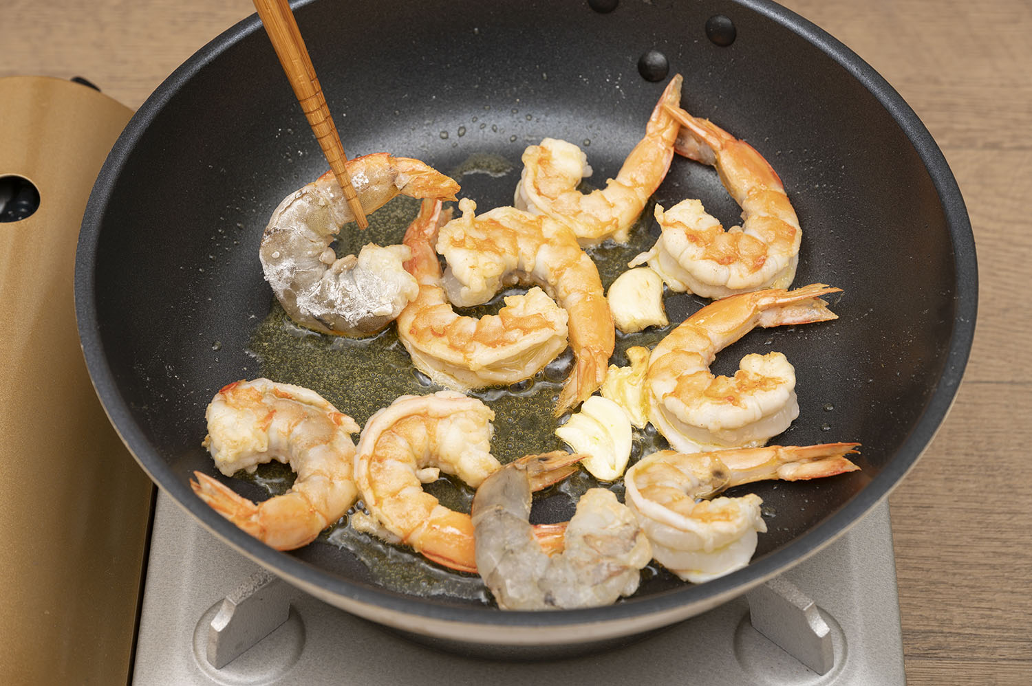 フライパンでオリーブ油とニンニクを入れ、弱火にかける。いい香りがしだしたら、中火にしてエビを加え両面に焼き色がつくまで焼く。