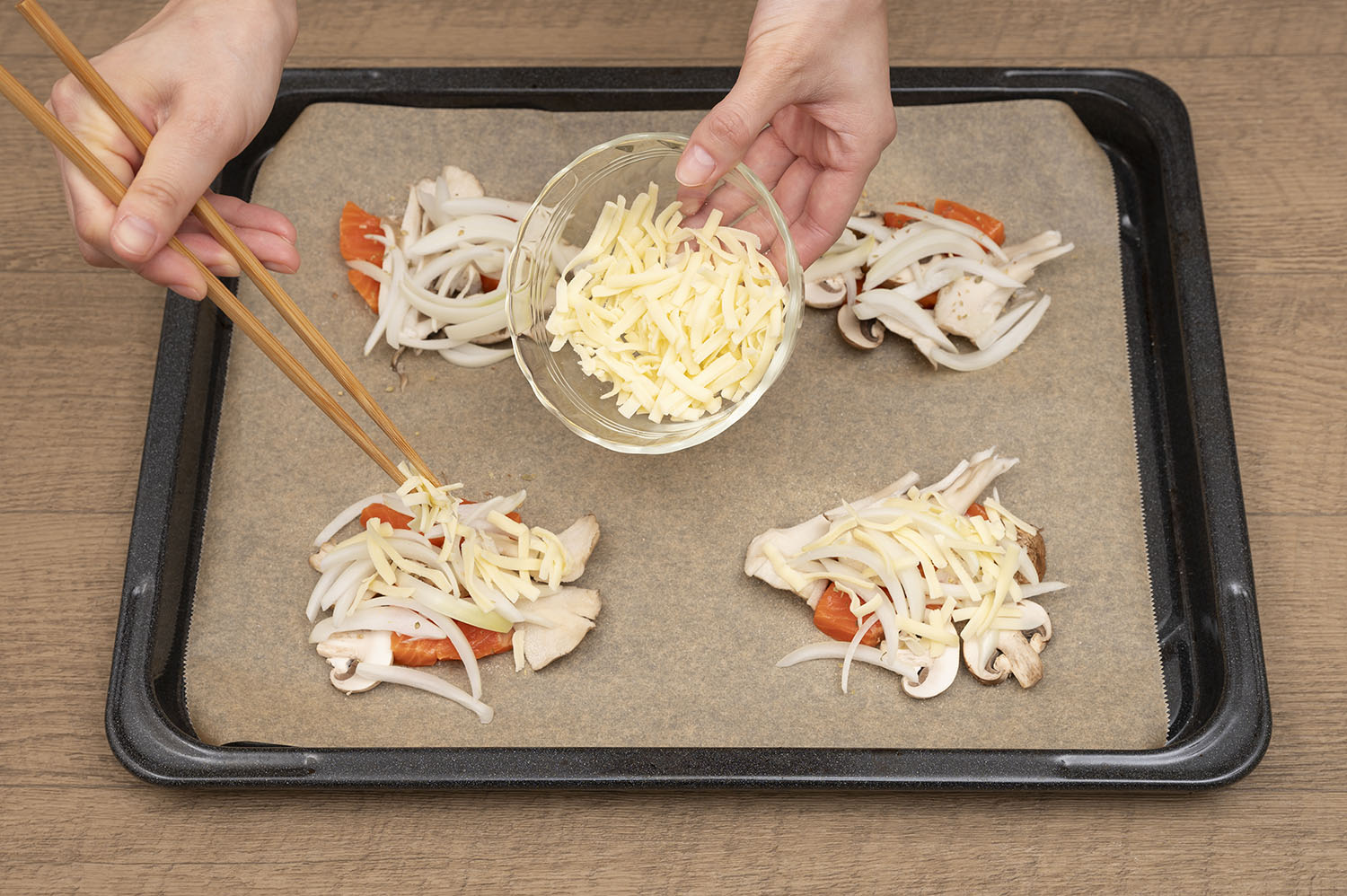 オーブンの天板にクッキングシートをしき、塩とコショウをふる。その上にサーモンと玉ねぎ、キノコをのせ、タイムをふり、ピザ用チーズをのせ、パイ生地をかぶせる。