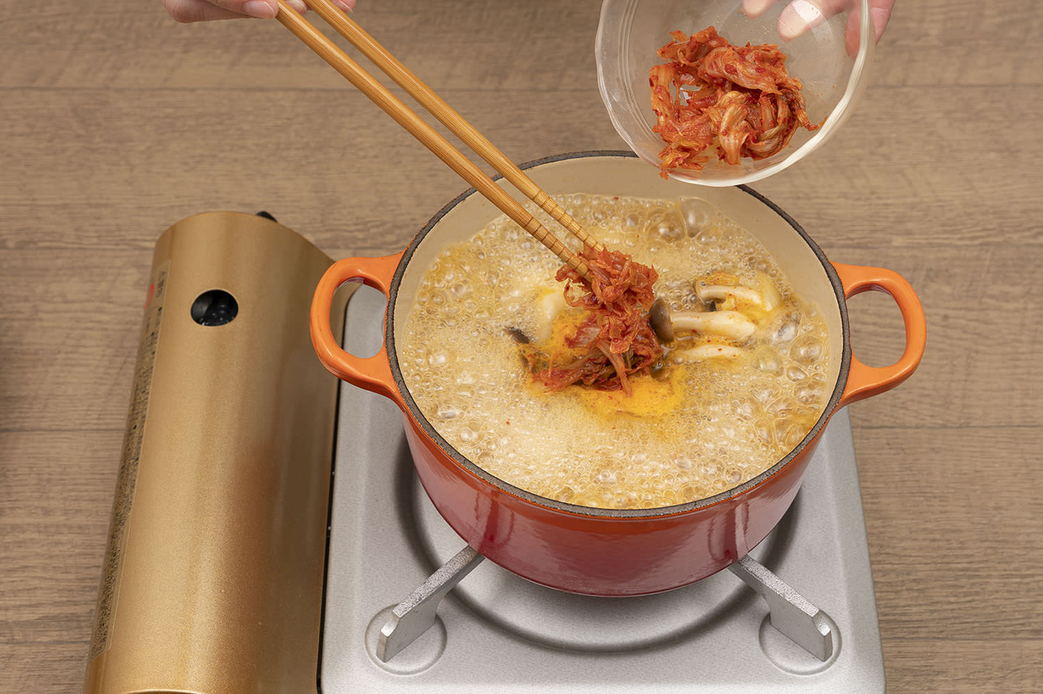 鍋にサラダ油と生姜とニンニクを入れて弱めの中火にかける。いい香りがしだしたら、長ネギと白菜キムチ半量を加えて炒め合わせる。